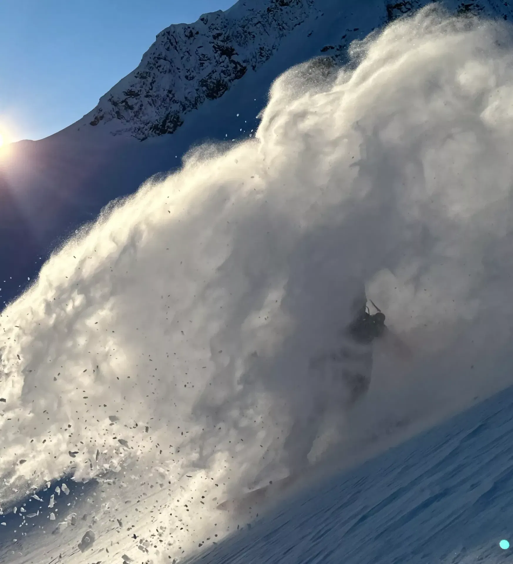Skieur disparaissant dans un nuage de poudreuse à contre-jour