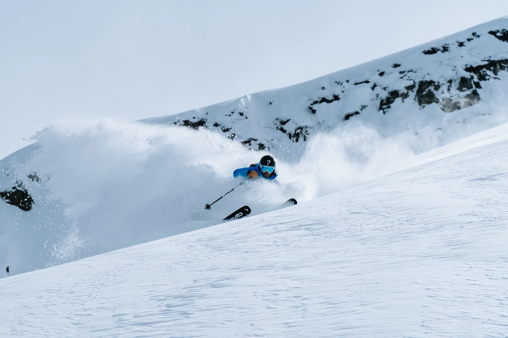 Skieur virant dans la poudreuse sous une crête rocheuse