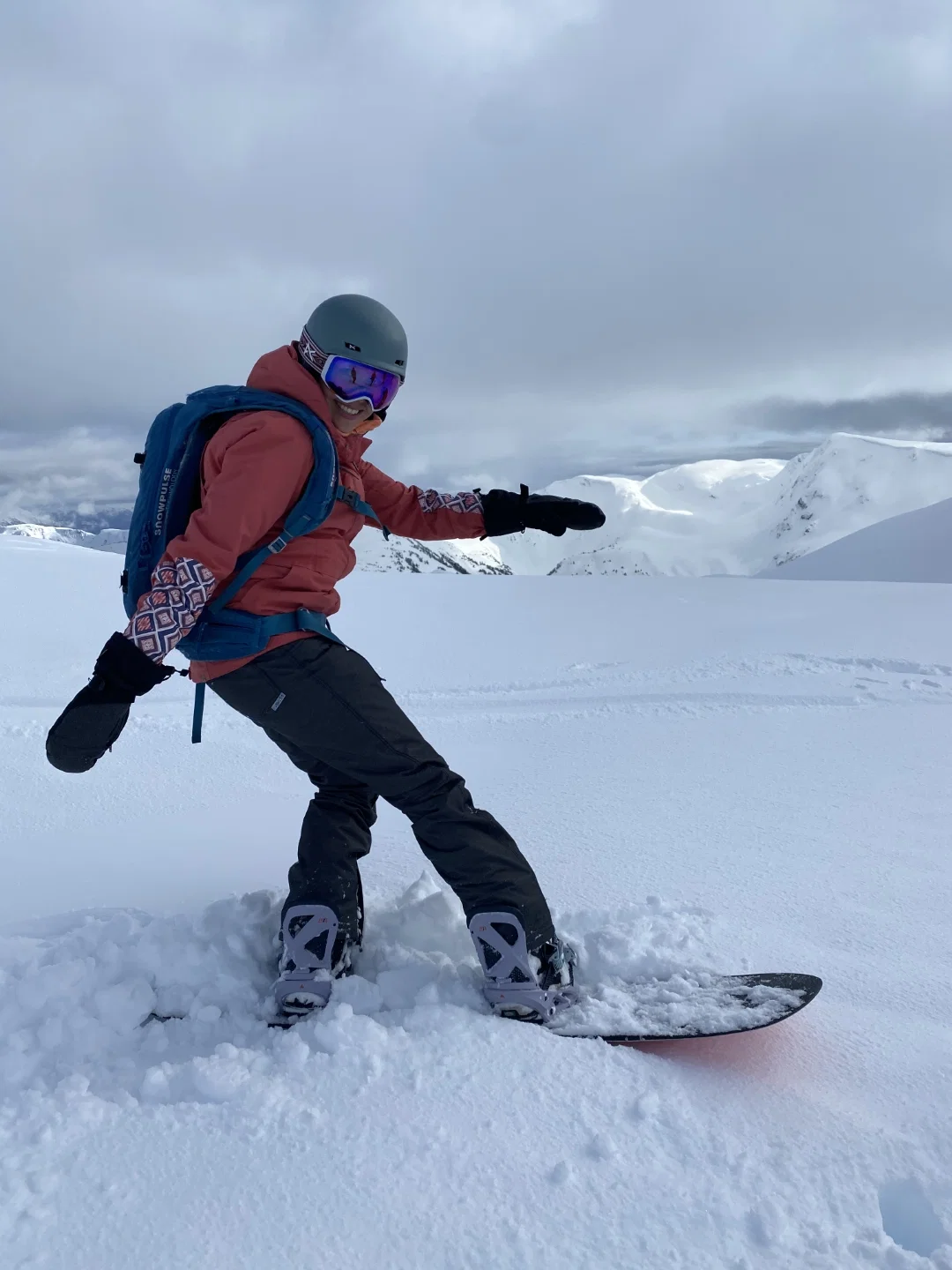 Snowboardeuse avec casque et sac à dos dans la neige profonde sur un plateau sommital